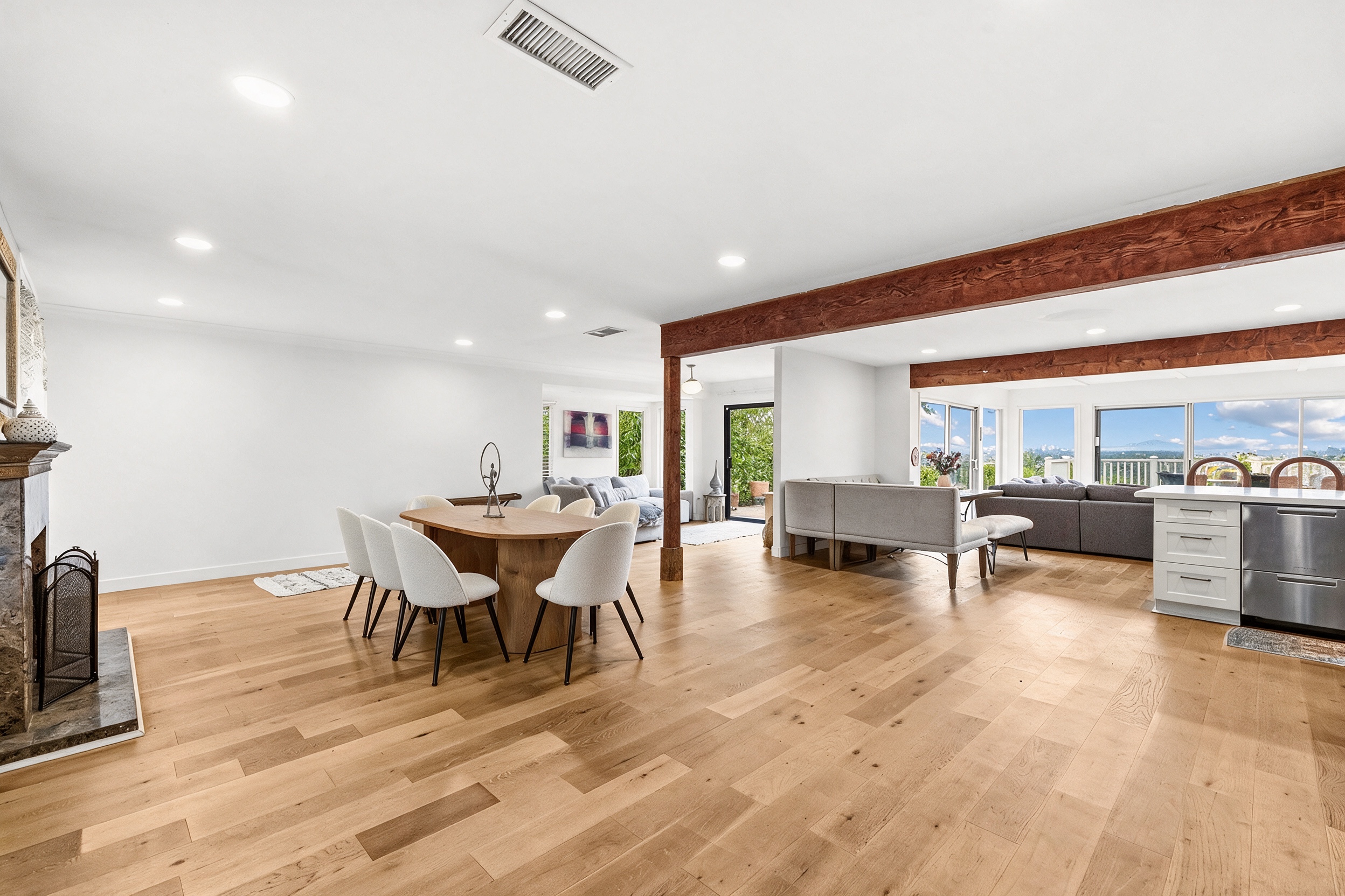 Open-concept great room with exposed wood beams and canyon views through floor-to-ceiling sliders