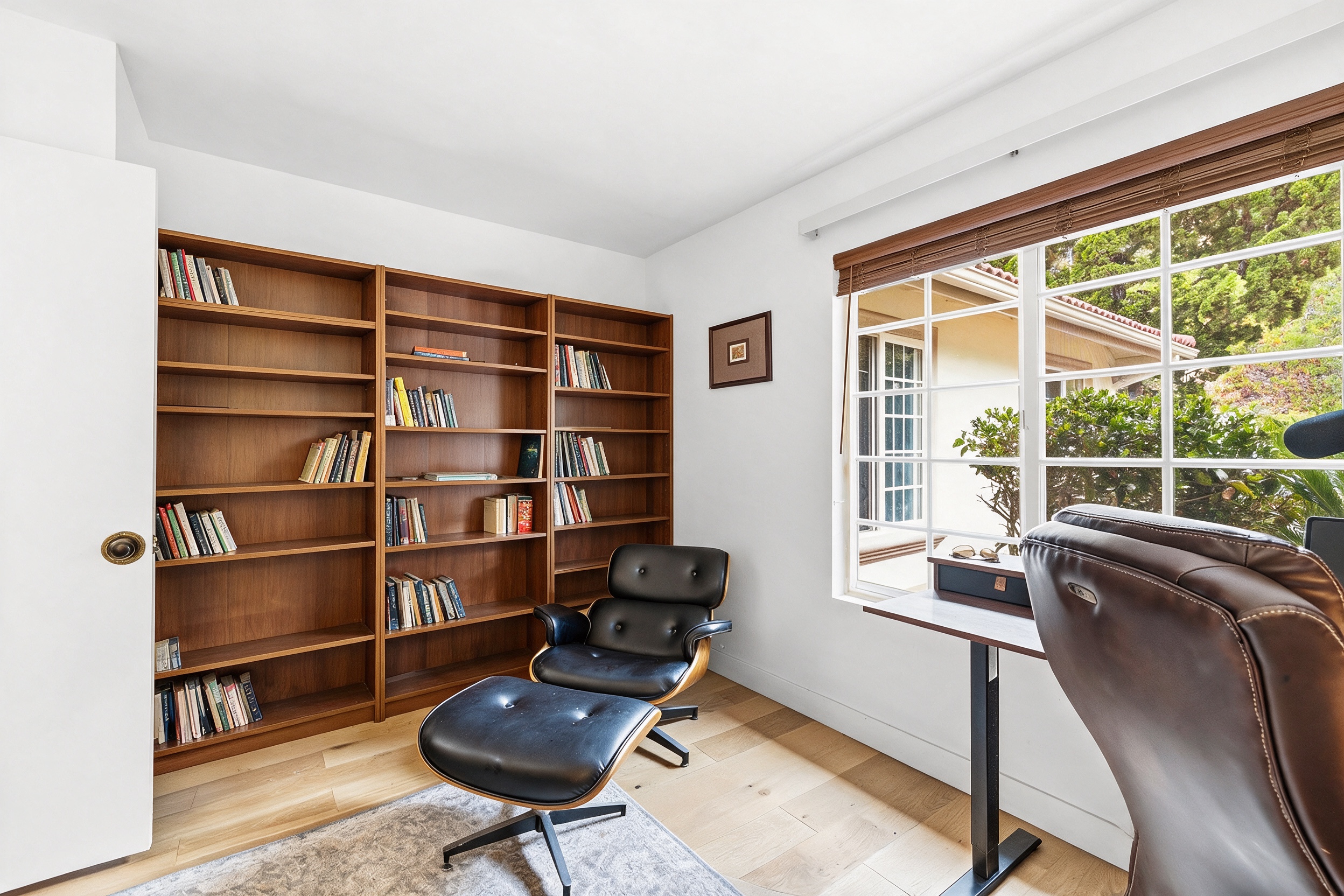 Home office with built-in library shelving and garden view